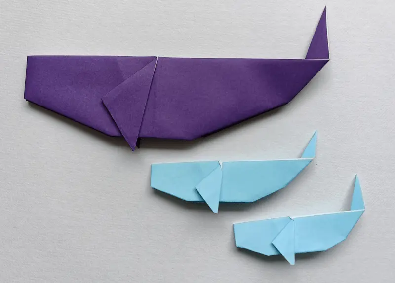 A real photo of a large blue parent whale and a smaller baby whale made with easy origami