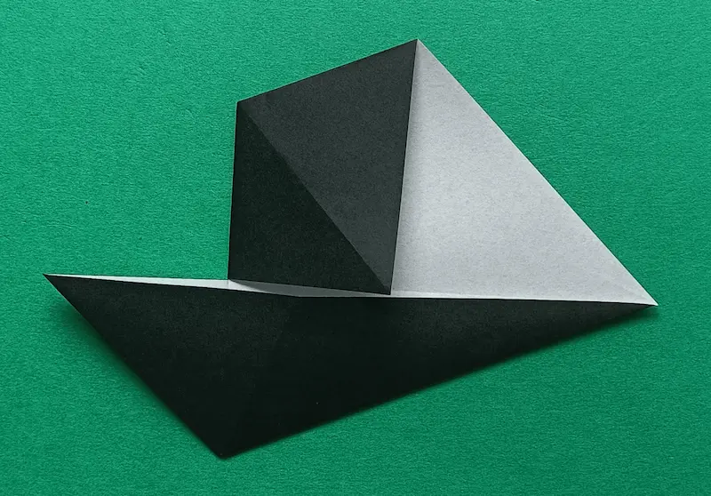 Put your finger in the bottom pocket, and fold it to meet the center crease